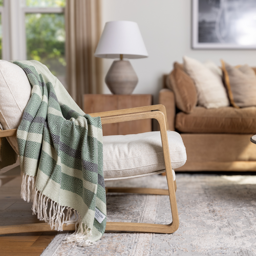 Modern living space with the Luxe Bamboo Stripe Throw in Fern & Forest, draped over soft neutrals—lush green tones anchoring the room in quiet elegance
